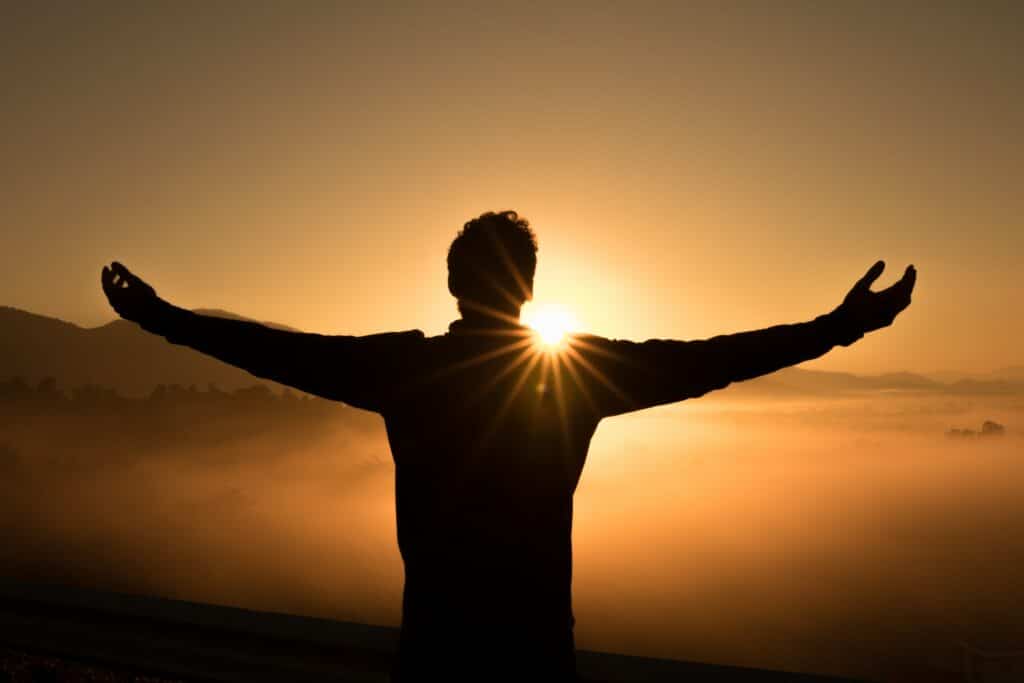 Spiritually wealthy man standing on mountain top with arms open