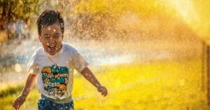emotionally wealthy kid running through sprinkler